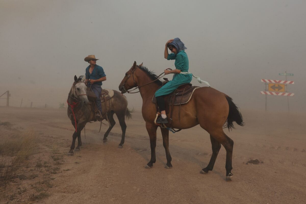 Isaac Slabaugh and Fannie Stutzman are surrounded by smoke from the Richard Spring Fire as it moves toward Ashland, Mont., Tuesday, Aug. 10, 2021. The fire burning on and around the Northern Cheyenne Indian Reservation has grown into Montana's largest blaze so far in 2021. (Mike Clark/The Billings Gazette via AP)