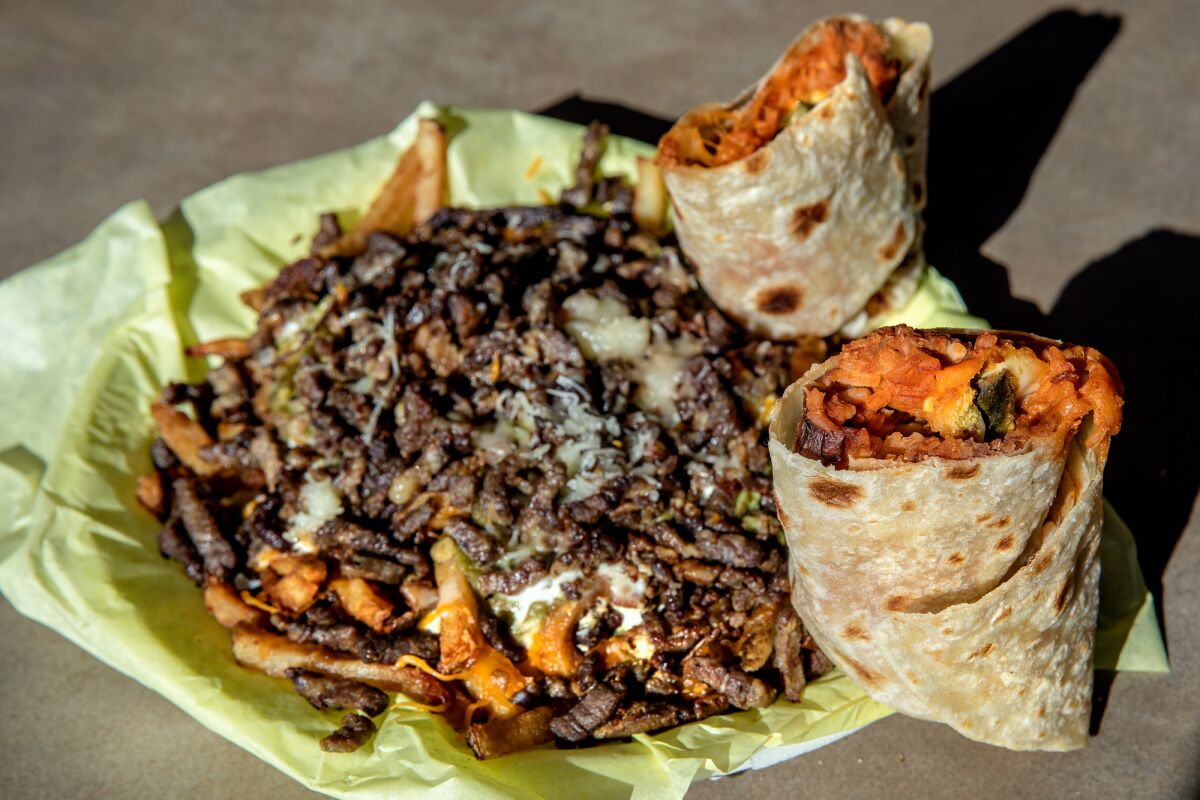 A chile relleno burrito and carne asada fries on a paper-topped plate