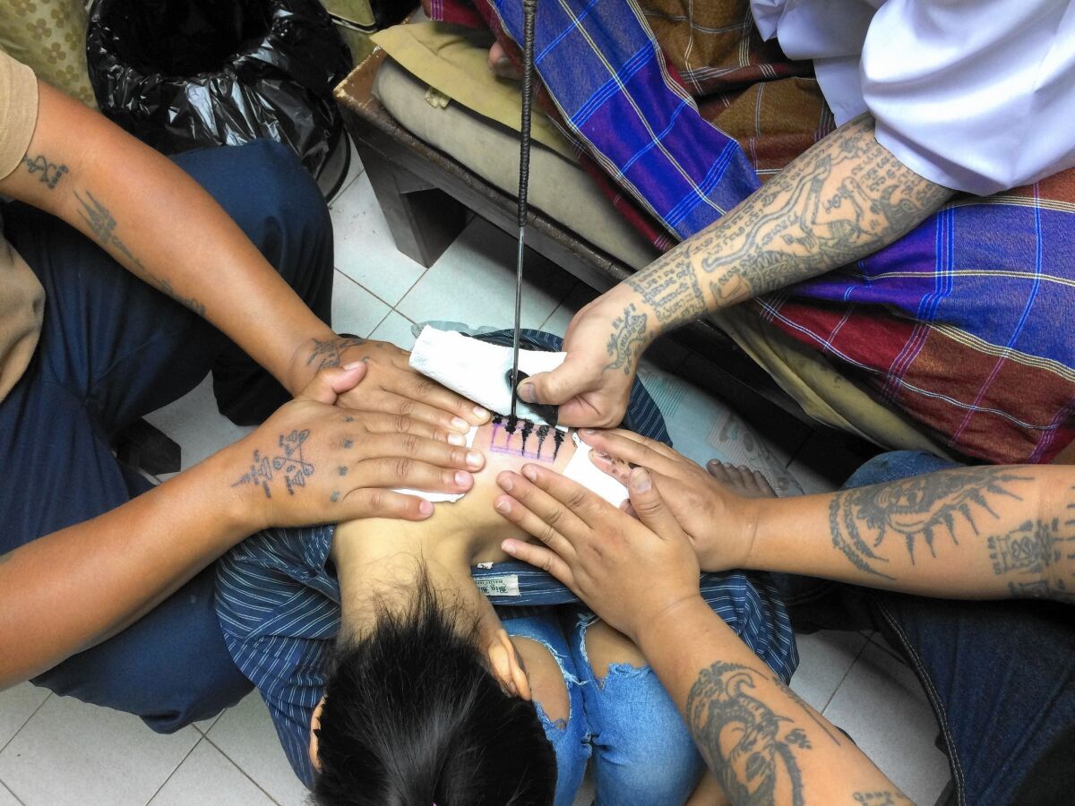Ajarn Neng, a spiritual sak yant tattoo master in Bangkok, tattoos five lines of Khmer script on one of his clients, meant to grant her protection from bad luck.