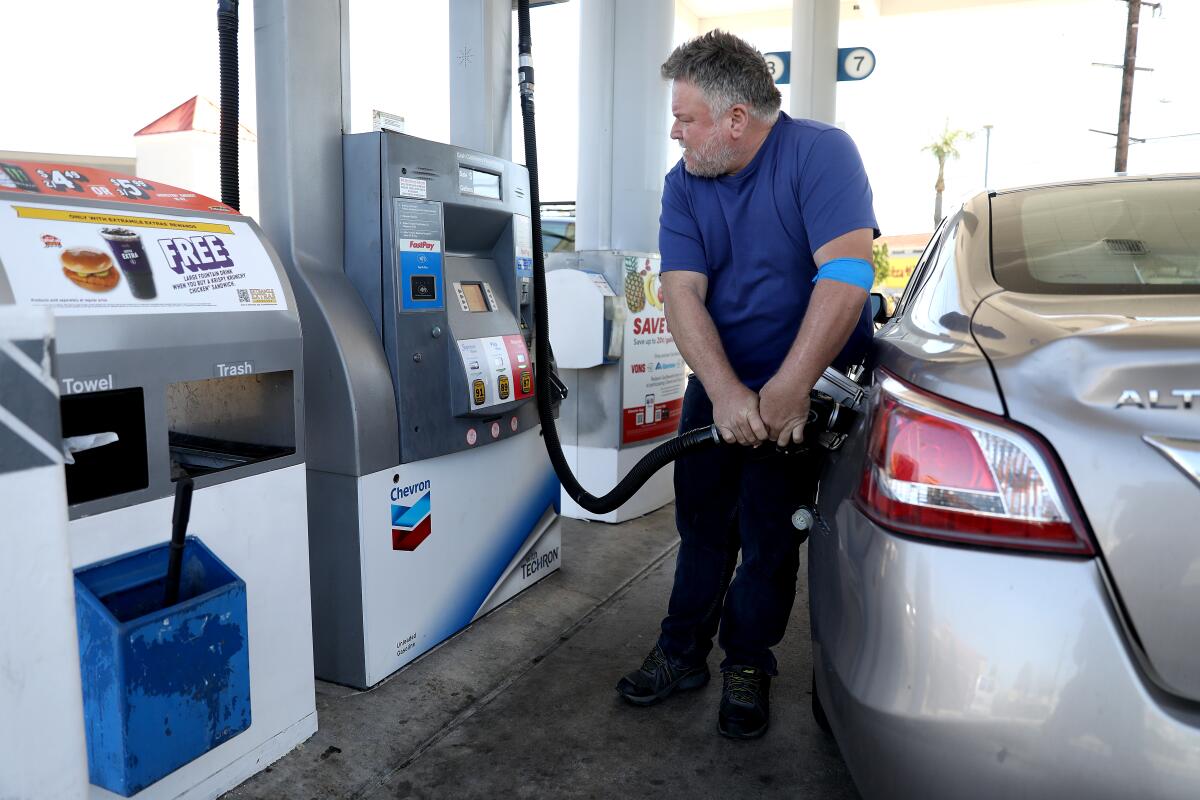 Joseph Starr, of Aliso Viejo, pumps gas into his automobile at a Chevron gas station in Orange.