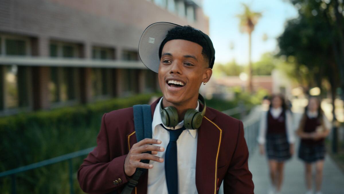 A teenager in a private school uniform with headphones around his neck