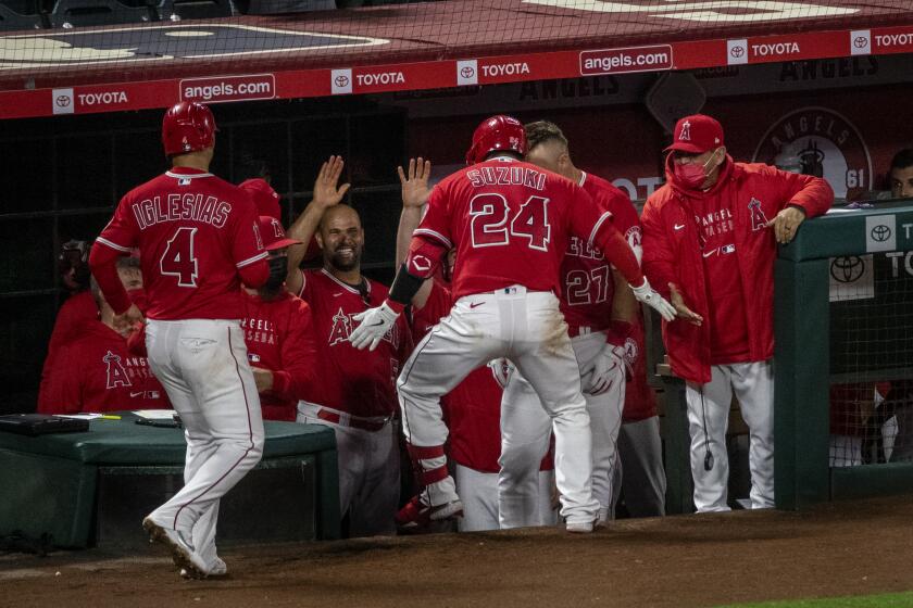 ANAHEIM, CA - APRIL 20, 2021: Los Angeles Angels catcher Kurt Suzuki (24) is congratulated art the dugout after hitting a 2-run home run against Texas Rangers starting pitcher Taylor Hearn (52) in the 7th inning at Angel Stadium on April 20, 2021 in Santa Ana California.(Gina Ferazzi / Los Angeles Times)
