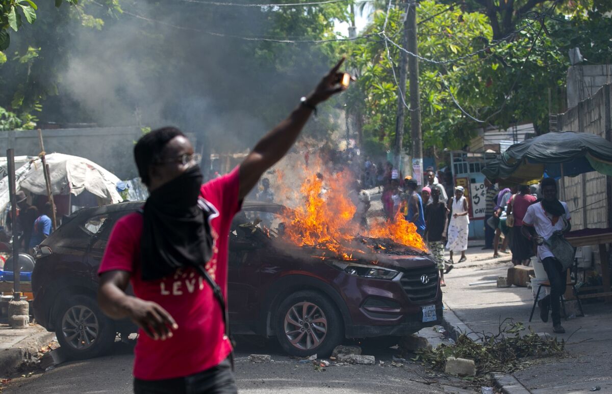 A protester holds up matches after setting a government car on fire during a protest demanding justice for a student who was gunned down by police the previous week at the university where students were protesting on campus for government teaching jobs in Port-au-Prince, Haiti, Monday, Oct. 5, 2020. (AP Photo/Dieu Nalio Chery)
