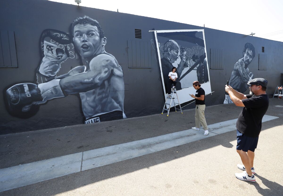  Artist Paul Jimenez takes a photo of fellow artist Singne Ditona and House of Boxing owner Carlos Barragan Jr.
