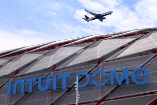 INGLEWOOD, CA - AUGUST 1, 2024 - A plane passes over the Intuit Dome Plaza in Inglewood on August 1, 2024. The sports stadium is still under construction. (Genaro Molina/Los Angeles Times)