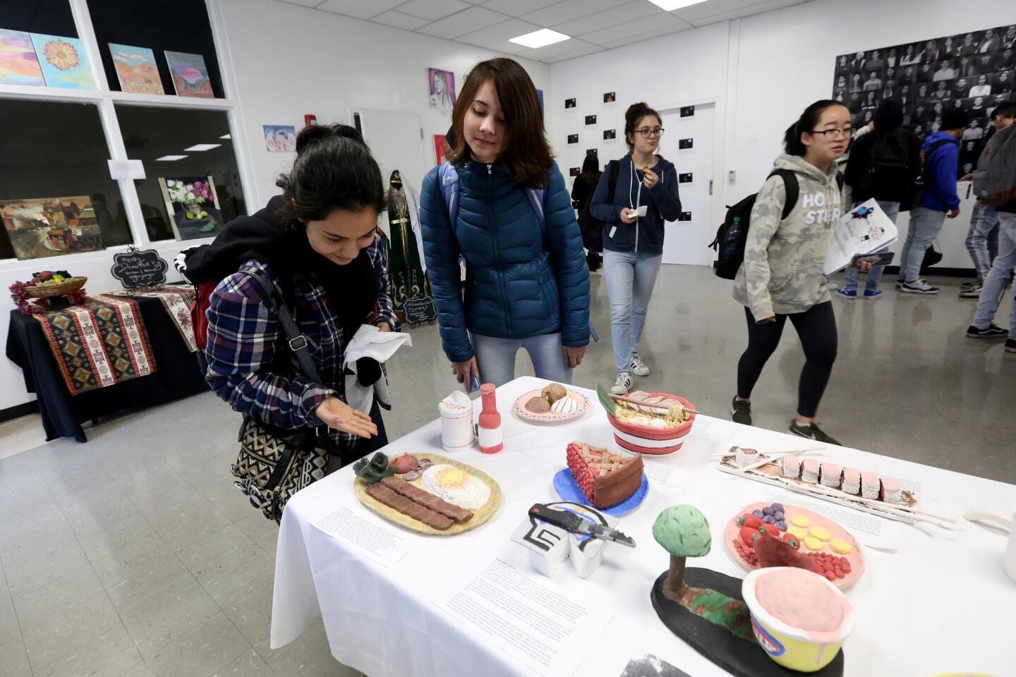 Juniors Anna Zadoorian, left, and Melissa McBryde, right, look at student ceramic work displayed at the inaugural student exhibition called Insight at Hoover High School in Glendale on Friday, Feb. 15, 2019. The event runs through March 31st.