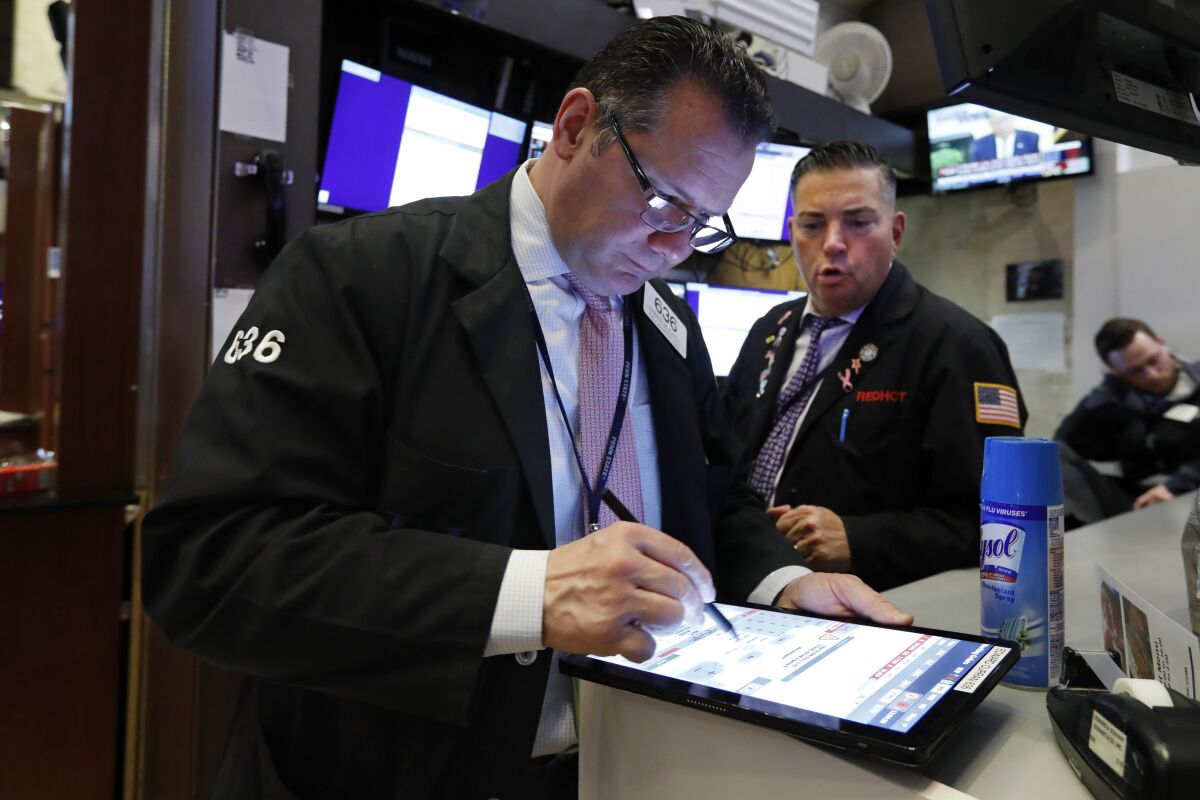 Traders Edward Curran, left, and Jonathan Mueller work on the floor of the New York Stock Exchange, Thursday, March 12, 2020. The deepening coronavirus crisis is sending stocks into another alarming slide on Wall Street, triggering a brief, automatic shutdown in trading for the second time this week. (AP Photo/Richard Drew)