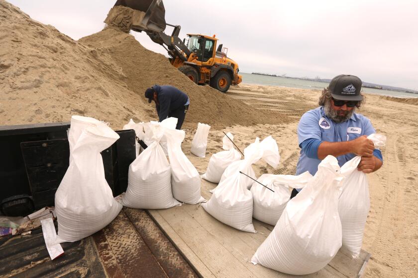 LONG BEACH, CA - FEBRUARY 3, 2024 - - Ryan Coppenger, right, and Scott Larson, with the City of Long Beach ;Marine Bureau, collect bags of sand to be delivered to a lifeguard station that usually floods in preparations for upcoming storm in Long Beach on February 3, 2024. Coppenger and Larson also delivered sandbags to residents who needed them. Officials across Southern California are warning residents to prepare for what could be "life threatening and damaging flooding," beginning Sunday. (Genaro Molina/Los Angeles Times)