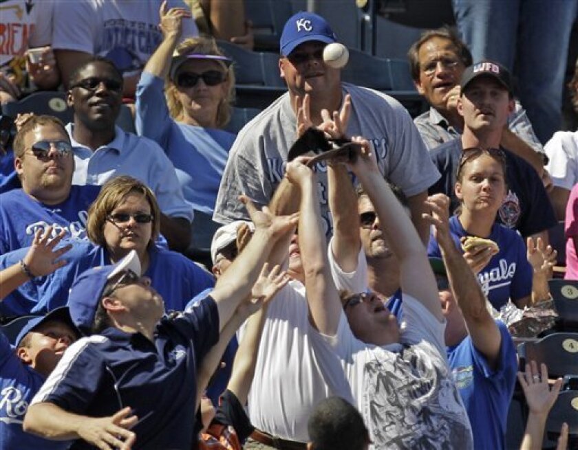 Fans battle for a foul ball hit by Kansas City Royals' Kila Ka'aihue during the fifth inning of a baseball game against the Detroit Tigers Sunday, Sept. 5, 2010 in Kansas City, Mo. (AP Photo/Charlie Riedel)