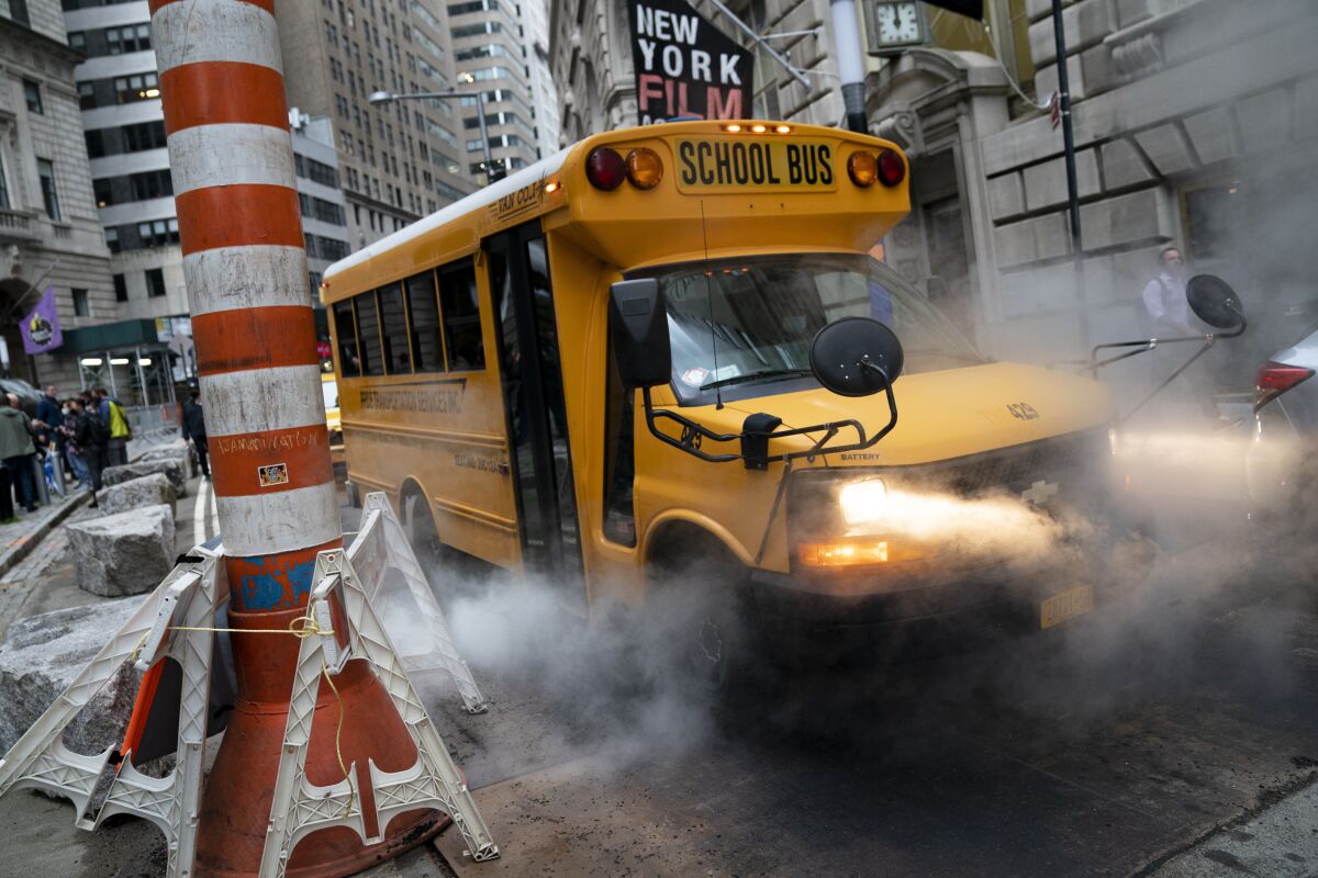 A school bus passes through a steam vent on a morning route, Monday, Oct. 4, 2021, in the Manhattan borough of New York. (AP Photo/John Minchillo)
