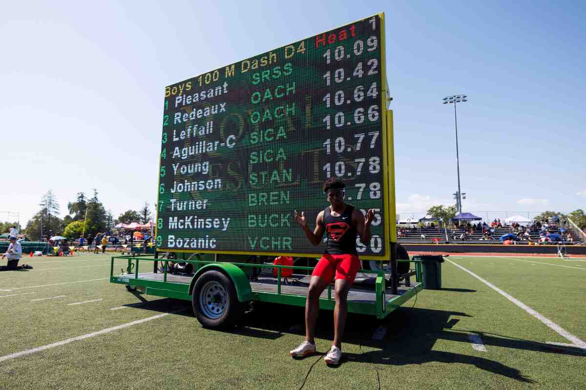 Rodrick Pleasant of Gardena Serra poses in front of scoreboard after running the fastest 100 time in California history.