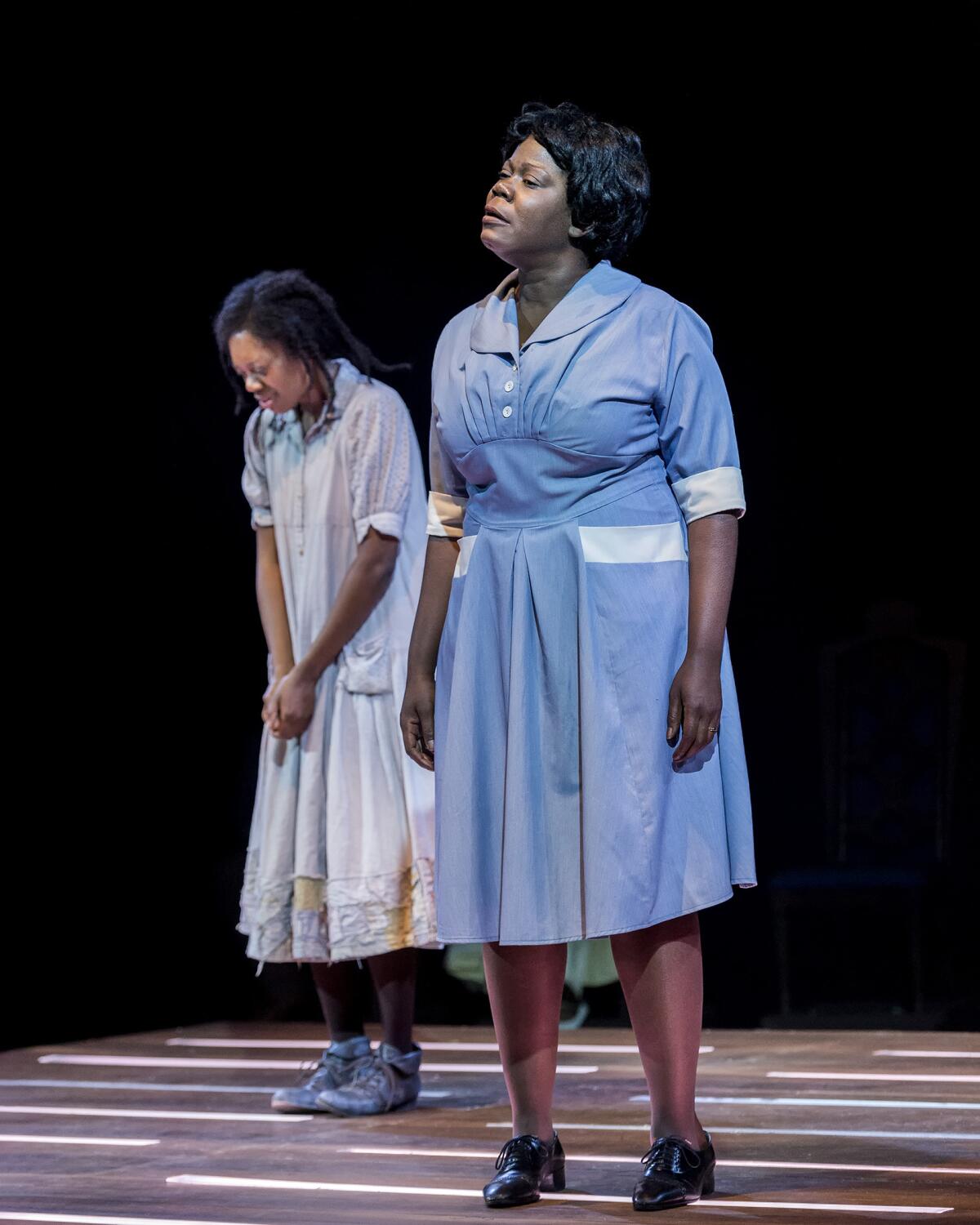 A woman in a maid's uniform stands next to a younger woman in a downcast posture.