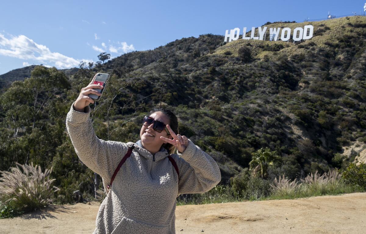 A woman takes a selfie in Griffith Park overlooking the Hollywood sign on March 27.