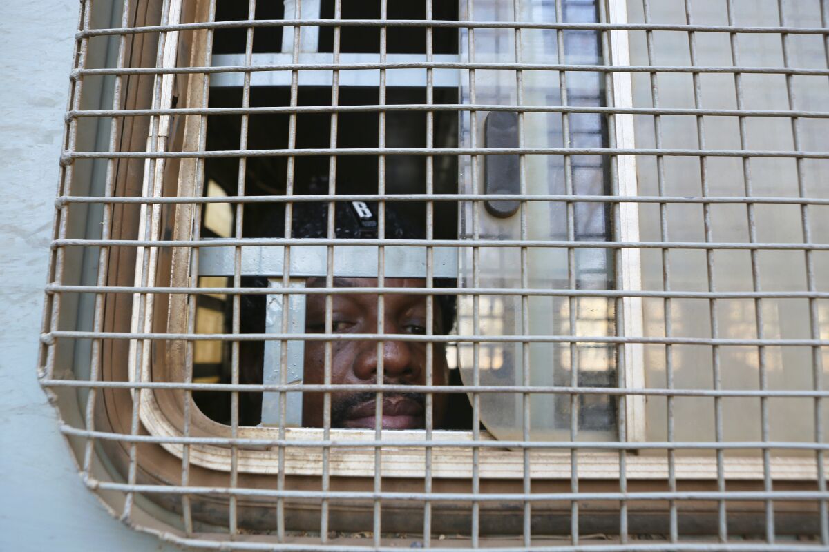 Zimbabwe Journalist Hopwell Chin'ono is seen through the window of a prison truck upon his arrival at the magistrates courts for his bail ruling in Harare, Monday, Aug, 24, 2020. A magistrate has denied bail to Chin'ono saying that they are no new circumstances to warrant bail for the freelance journalist who has been in custody for over a month. Chin'ono is accused of mobilizing anti government protests and is among more than 100 100 government critics who have been arrested in recent months ,according to human rights groups.(AP Photo/Tsvangirayi Mukwazhi)