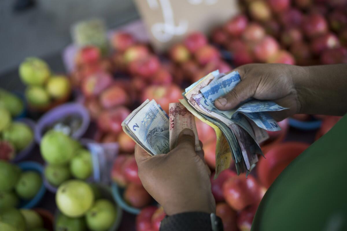 Un vendedor de frutas cuenta sus billetes de reales en un mercado en la calle en Río de Janeiro, Brasil, en esta foto del 24 de septiembre de 2014. Ahora, los brasileños están restringiendo los viajes a Estados Unidos, a donde enormes grupos iban de compras en los últimos años, lo que los convertía en la nacionalidad que gastaba más per cápita de todos los turistas extranjeros, según información del gobierno de Estados Unidos.