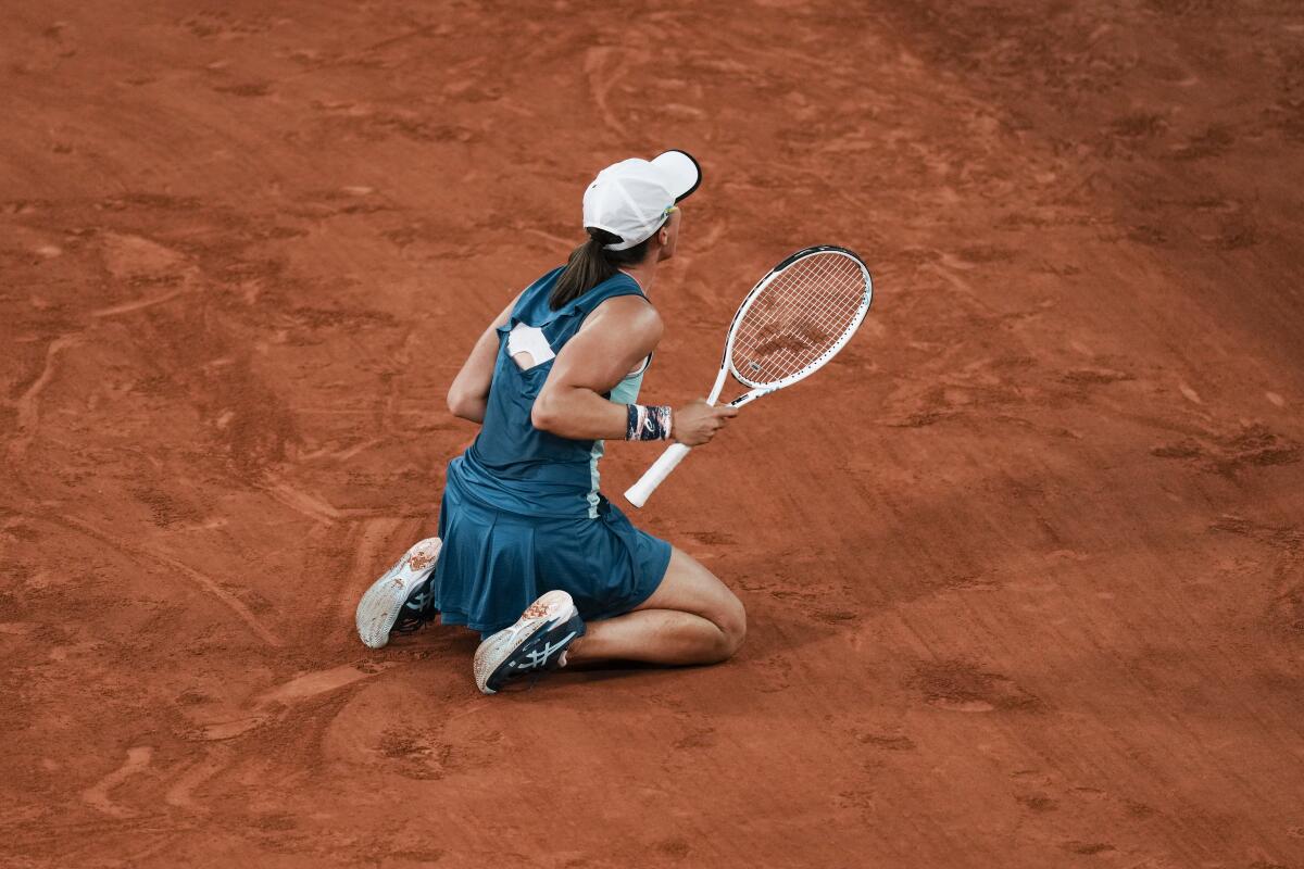 Poland's Iga Swiatek kneels on the court after winning.