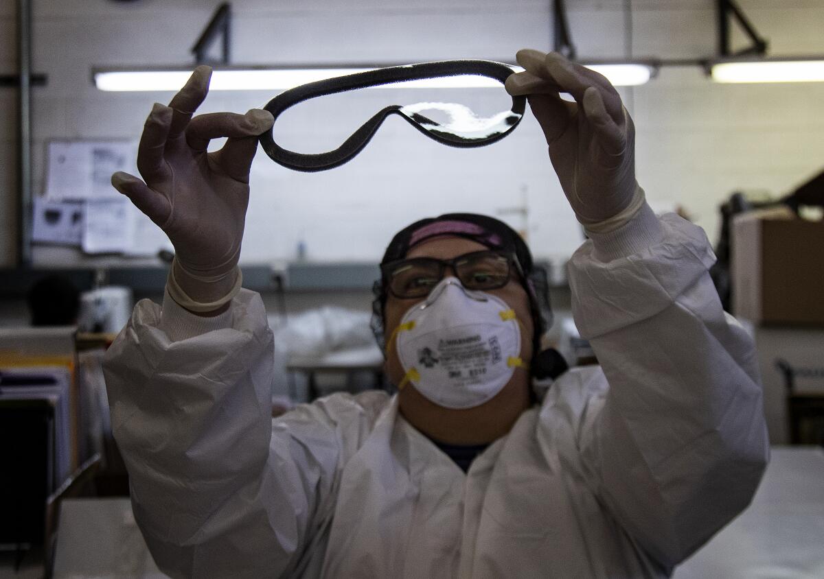 A worker in Temecula, California, in February checks for imperfections on a pair of medical goggles assembled for shipment to China to help prevent the spread of the coronavirus.