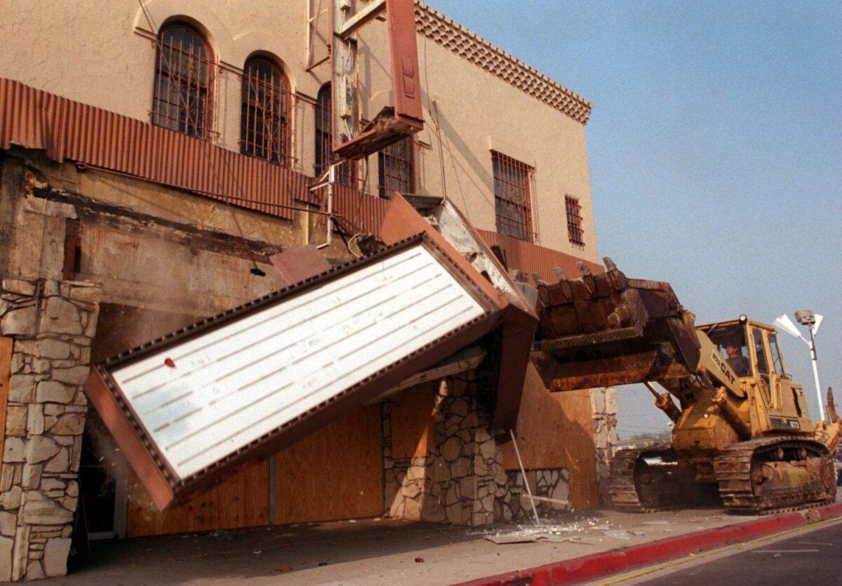 A bulldozer knocks down the marquee of the Pussycat Theater in Buena Park in 1995 after years of legal challenges. (Kari Rene Hall / Los Angeles Times)