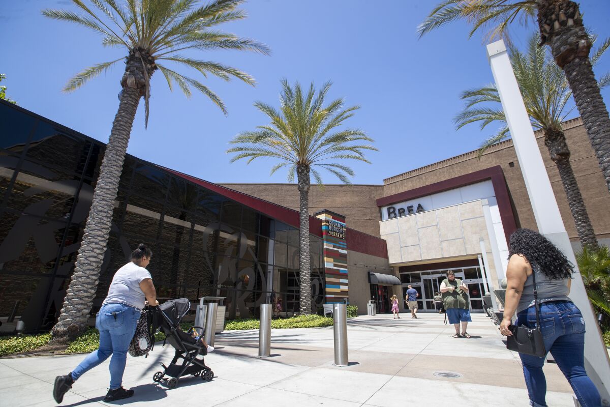 Shoppers come and go from the Brea Mall, which reopened Tuesday.