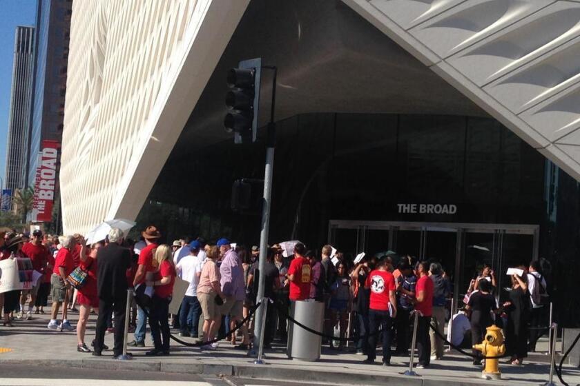 Protesters in red shirts join opening-day ticket holders outside the Broad art museum in downtown Los Angeles. As fans of contemporary art filled the galleries inside, protesters outside criticized museum founder Eli Broad for his support of charter schools.