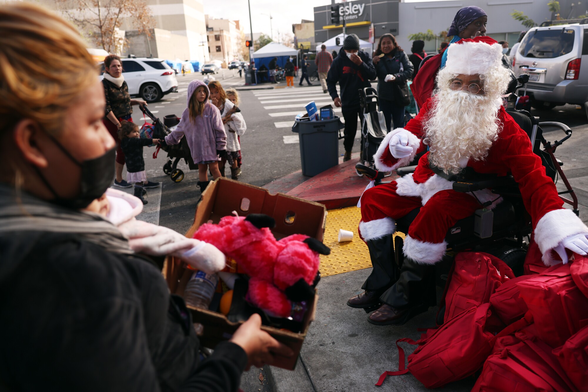 ریموند آلن گریر، با لباس بابانوئل، کوله پشتی های پر از لباس های گرم را به دست می دهد.