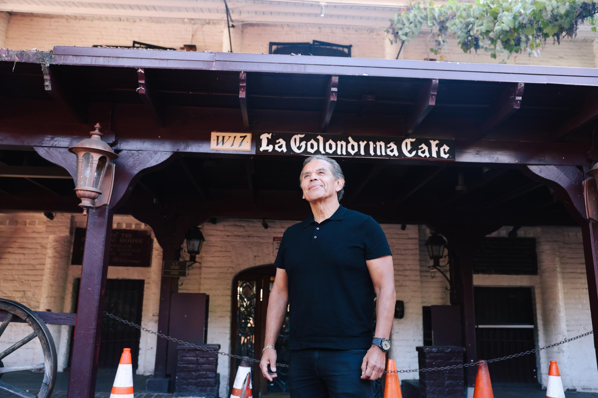 A man stands under a sign that says "La Golondrina Cafe."