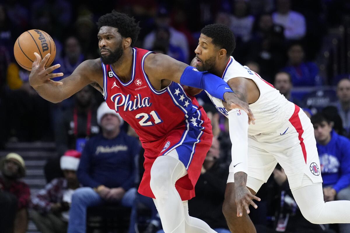 Philadelphia center Joel Embiid tries to hang on to the ball while pressured by Clippers forward Paul George.