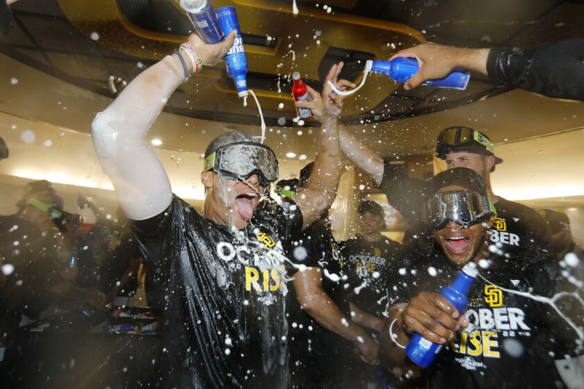 San Diego Padres players drench Juan Soto with drinks in the locker room after the team clinched a wildcard playoff spot during against the Chicago White Sox at Petco Park on Sunday, October 2, 2022 in San Diego, CA.
