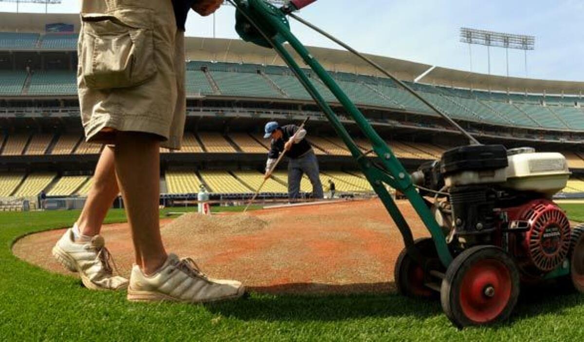 Staff workers get the field ready before an opening day game at Dodger Stadium.