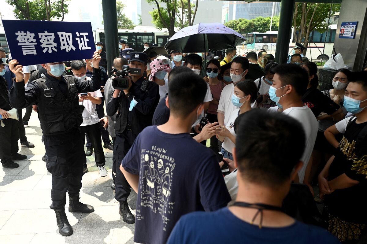 Police officers look at people outside the Evergrande headquarters