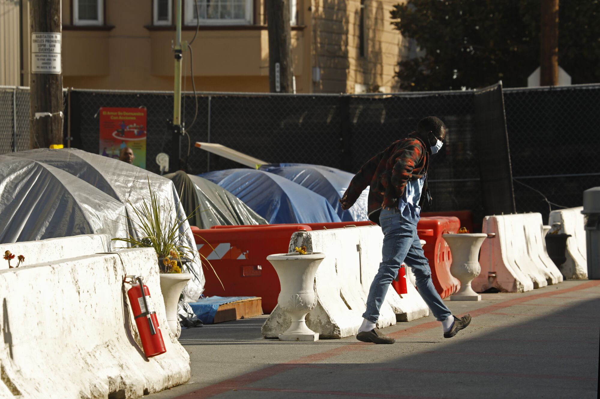 A person in a mask walks by a row of tents