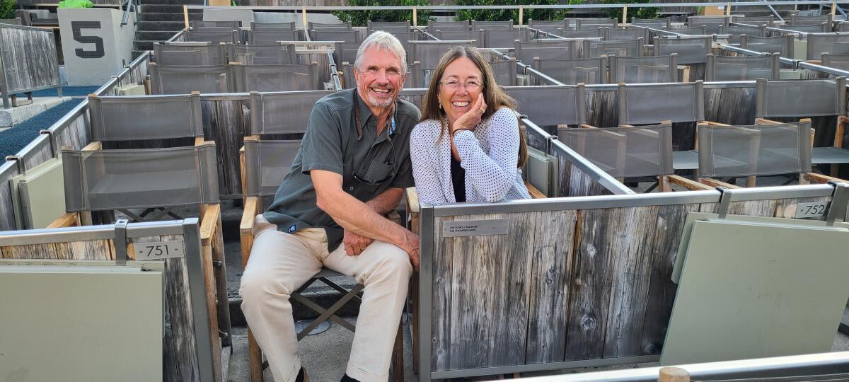 A smiling man and woman sit in box seats at the Hollywood Bowl.