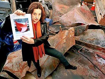 Victoria Leacock, a volunteer at the World Trade Center site, has been encouraging clean-up crews to save pieces of Alexander Calder's "Bent Propeller" sculpture. She is standing amid some of the pieces, holding a flyer she gives to the workers.