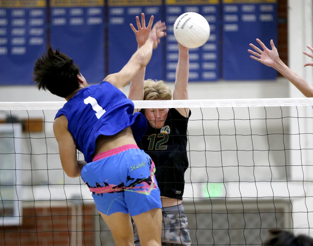 Thomas Ho of Fountain Valley (1) hits a kill past Edison's Ben Winokur during a Wave League boys' volleyball match.