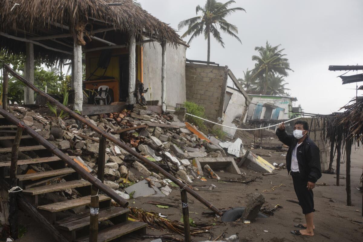 Un hombre inspecciona los daños después de que una parte de su casa fuera derribada por los vientos