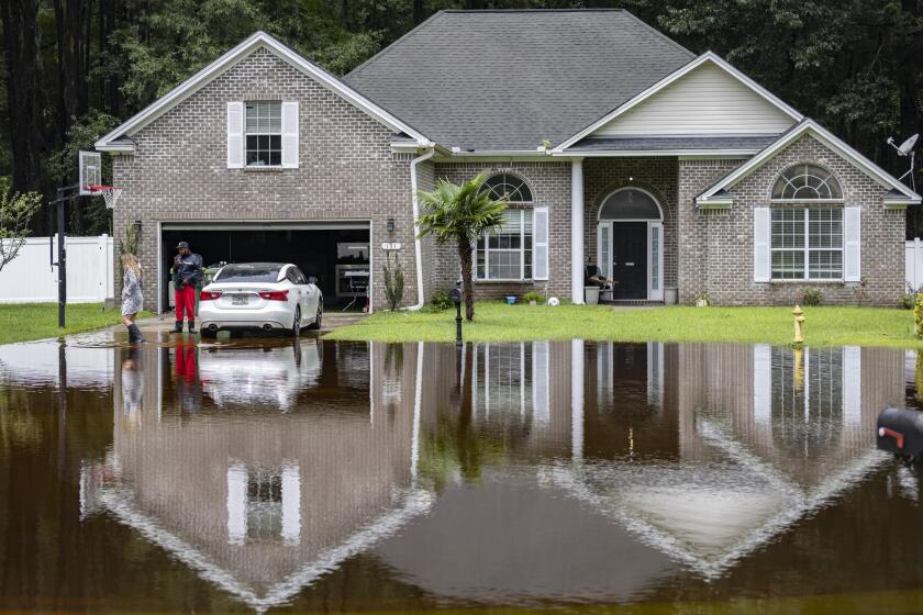 Keon Johnson y su esposa, Zyla Johnson, a la izquierda, hablan sobre cómo llegar a trabajar dado que su casa se ha inundado por las lluvias de la tormenta tropical Debby, el miércoles 7 de agosto de 2024 en Pooler, Georgia. (AP Foto/Stephen B. Morton)