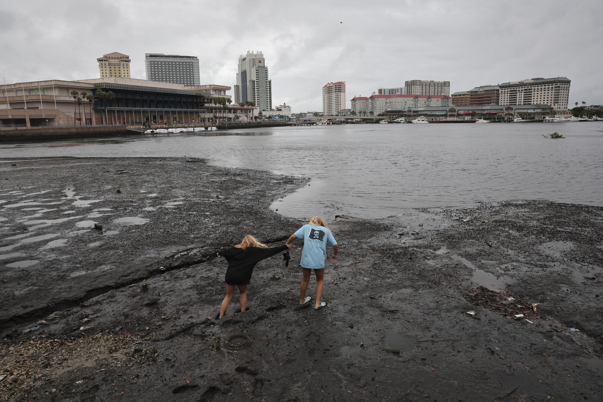 Sisters Angel Disbrow, right, and Selena Disbrow walk along the shore of Tampa Bay in Florida.