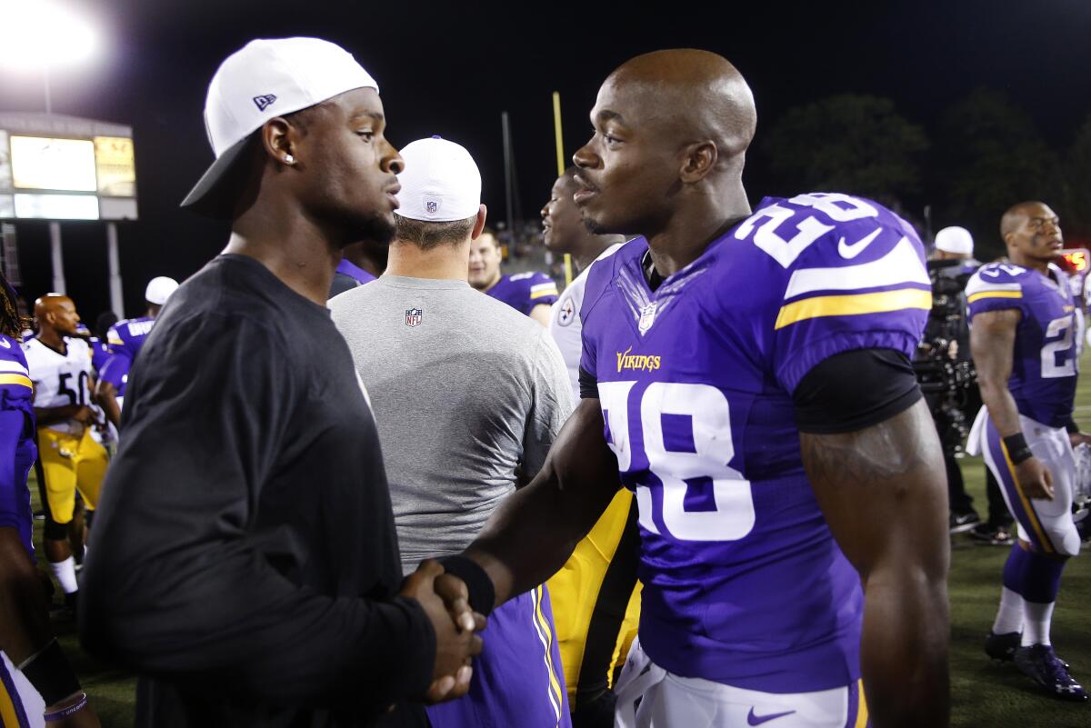FILE - Minnesota Vikings running back Adrian Peterson, right, visits with Pittsburgh Steelers running back Le'Veon Bell, left, on the field after an NFL preseason football game in Canton, Ohio, Sunday, Aug. 9, 2015. Adrian Peterson still wants to play in the NFL after he fights Le’Veon Bell in the boxing ring. The four-time All-Pro running back Peterson is taking on the two-time All-Pro back Bell on Saturday night at Crypto.com Arena in Los Angeles. It’ll be the first boxing match for the former NFL stars. (AP Photo/Tom E. Puskar, File)