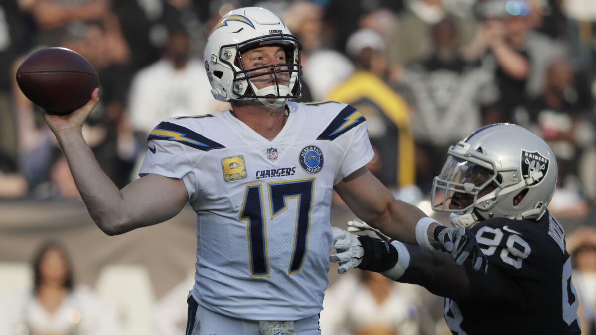 Chargers quarterback Philip Rivers launches a pass as he is pressured by Raiders defensive tackle Frostee Rucker.
