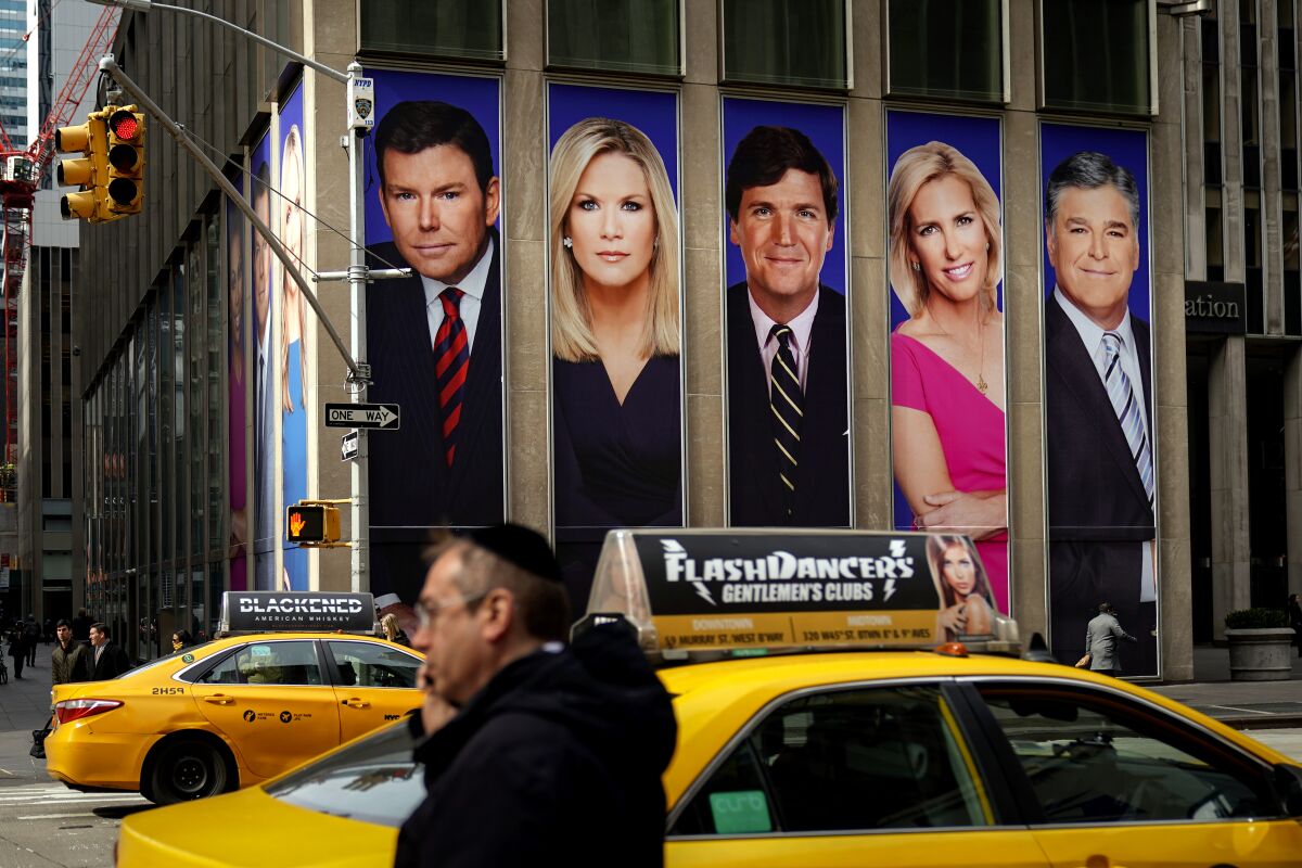 Traffic on Sixth Avenue passes by advertisements featuring Fox News personalities
