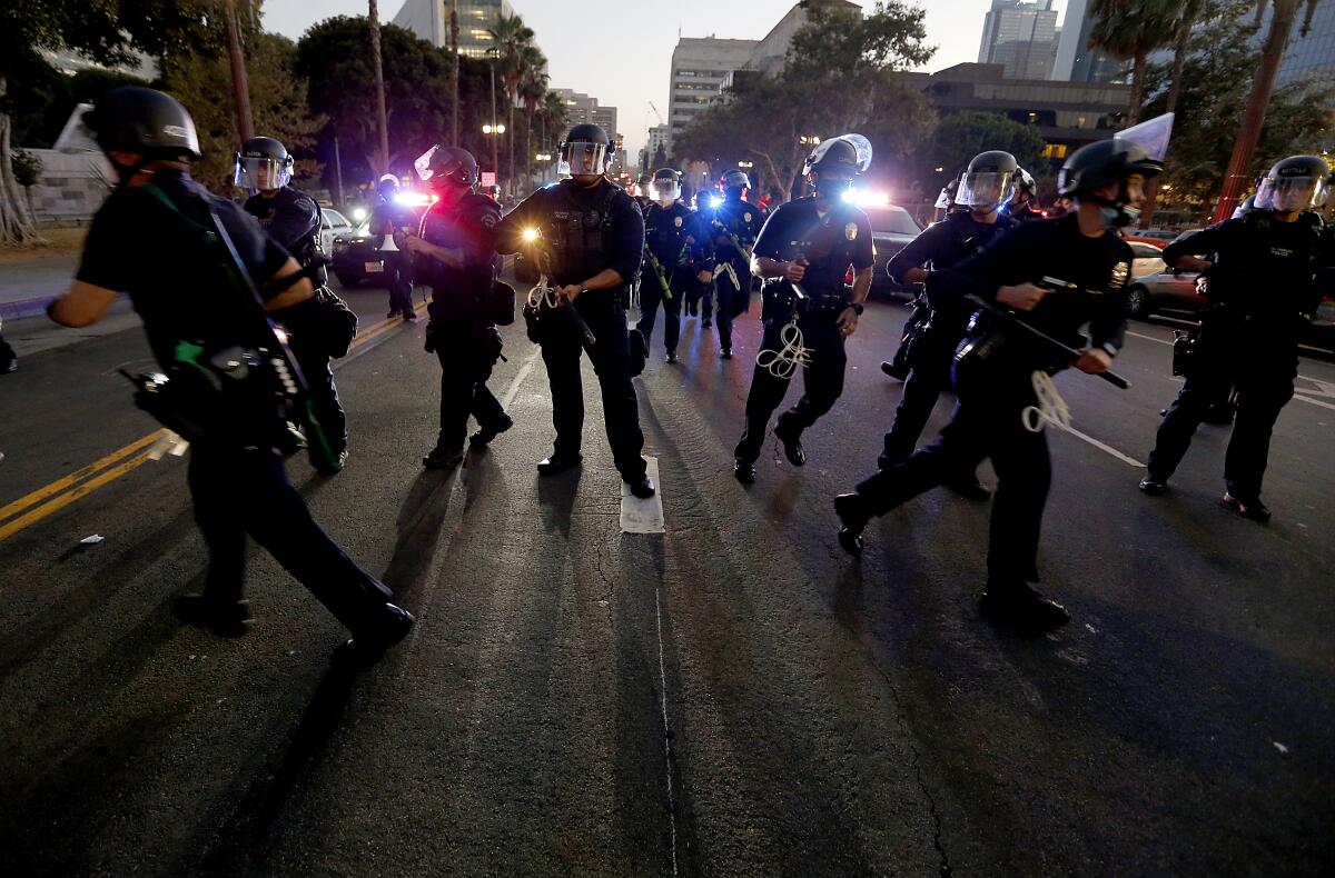 LAPD officers scramble to form a line against protesters.