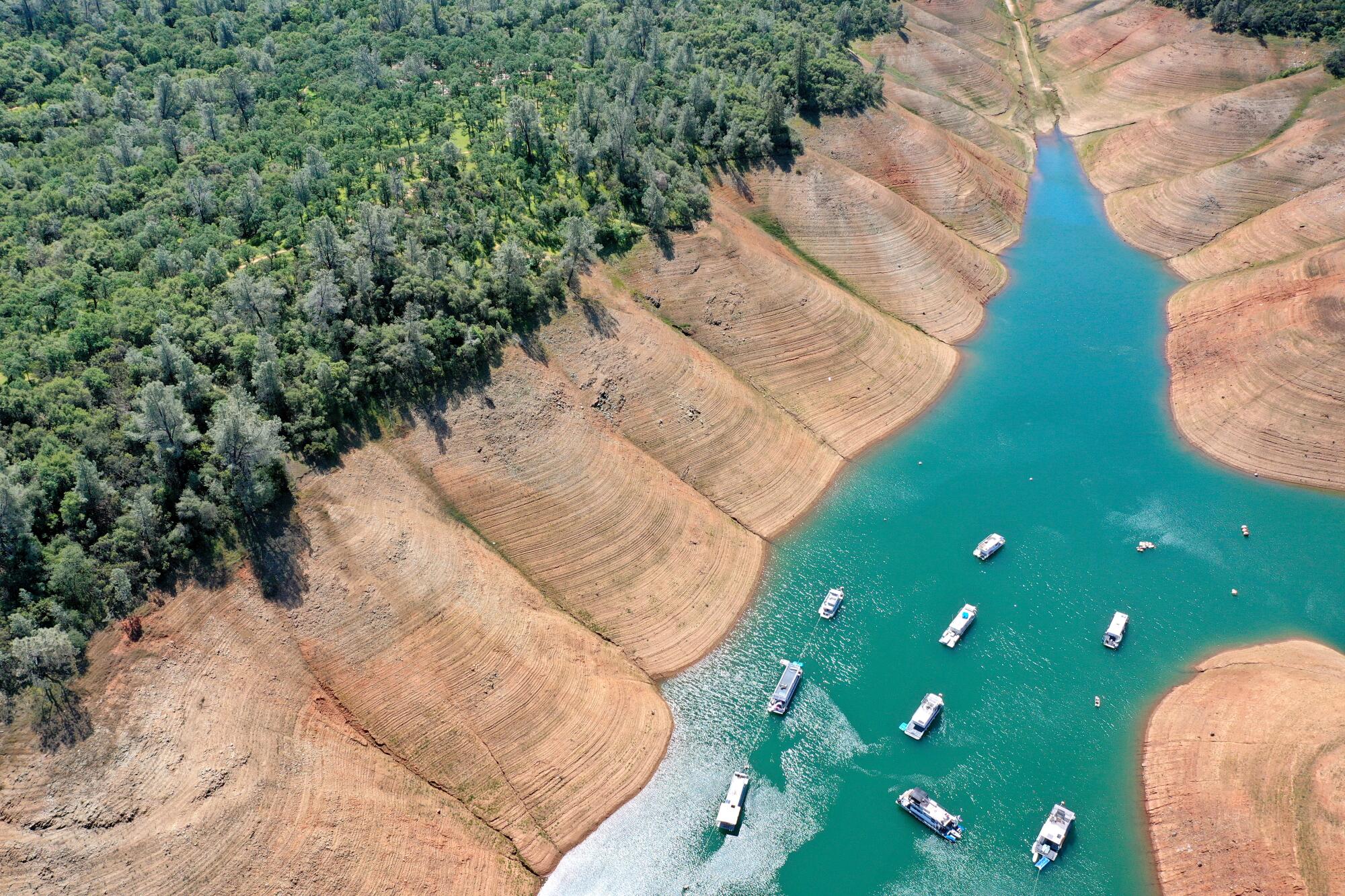 Houseboats are dwarfed by the steep banks of Lake Oroville.