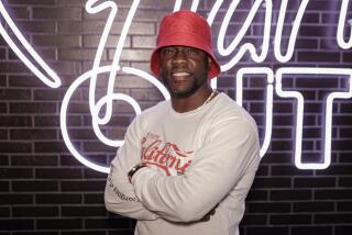 A man in a bucket hat smiles while posing with arms crossed in front of a tiled wall