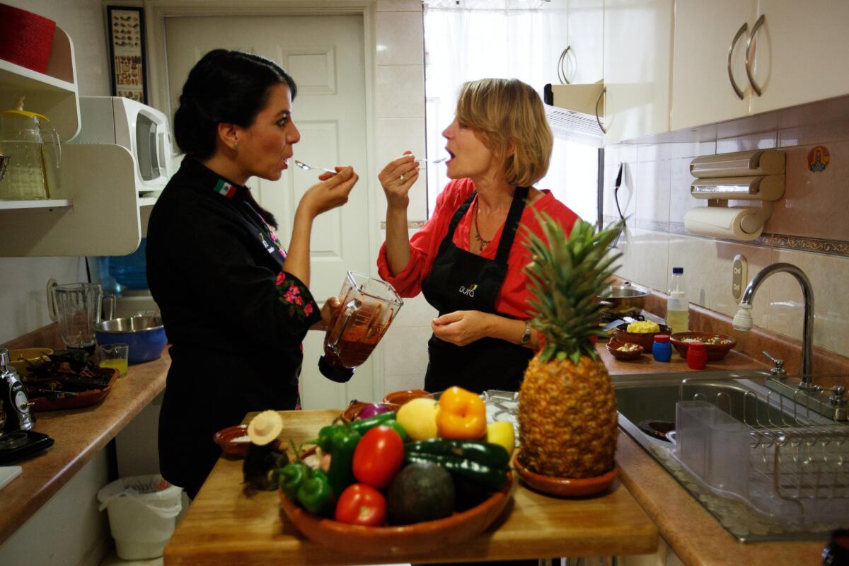 Graciela Montaño, left, and Liz Elliot taste-test a meal in progress in an Aura Club de Maridaje cooking class in Mexico City.