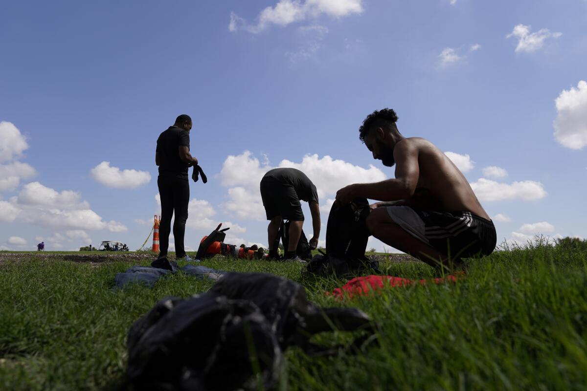 Migrantes reúnen sus objetos personales mientras esperan a ser procesados por la Patrulla Fronteriza 