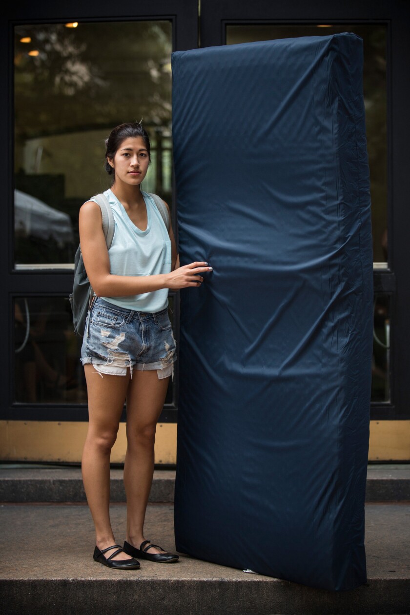 Emma Sulkowicz, a senior visual arts student at Columbia University, poses in 2014 with a 50-pound mattress, which she carried around campus for several months to protest the university's lack of action after she reported being raped during her sophomore year.