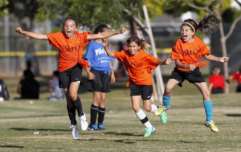 Davis players, Karli Rask, Erin Galvin, and Sophia De Marzo, left to right, jump for joy after Rask kicked in a goal against Our Lady Queen of Angels in a Daily Pilot Cup girls thrid- and fourth -grade gold division game Wednesday.