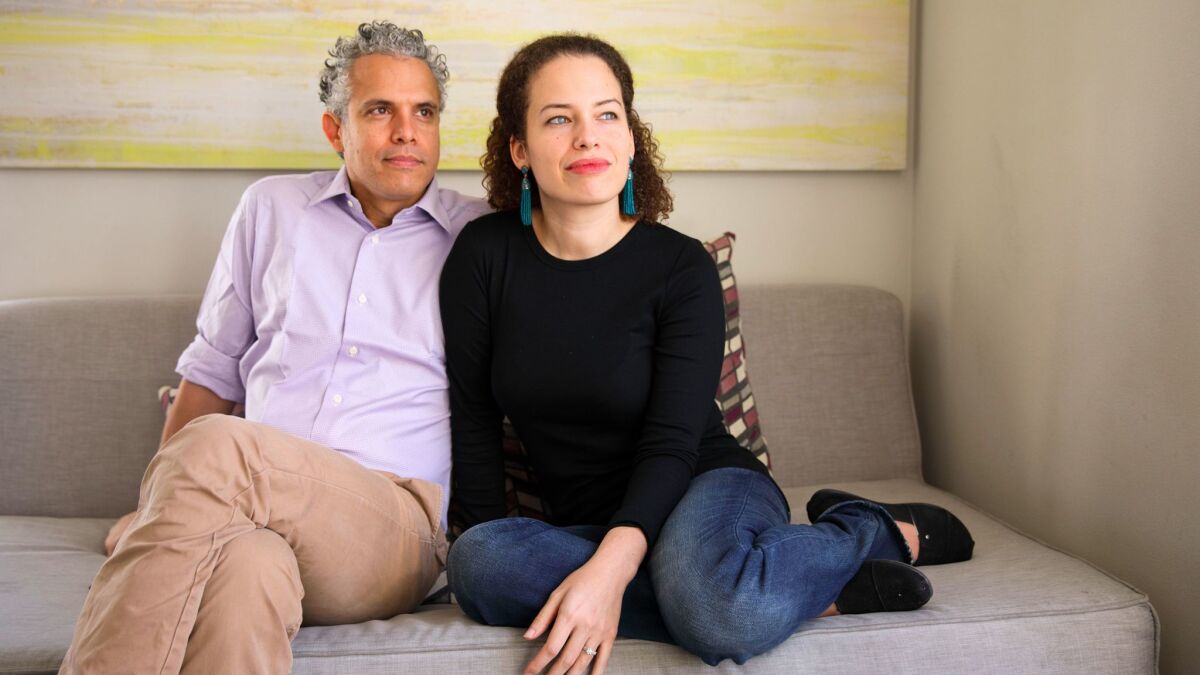 Omar Wasow and his wife, Jennifer Brea, sit for a portrait at their apartment building in Glendale.