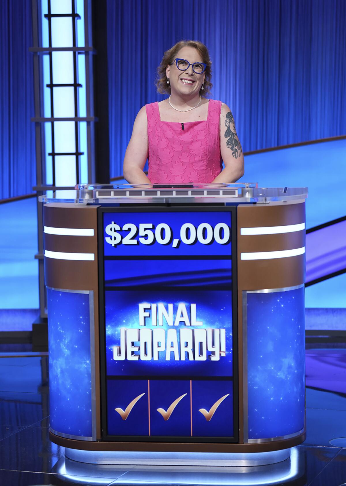 A woman with glasses in a pink strapless dress standing on at podium