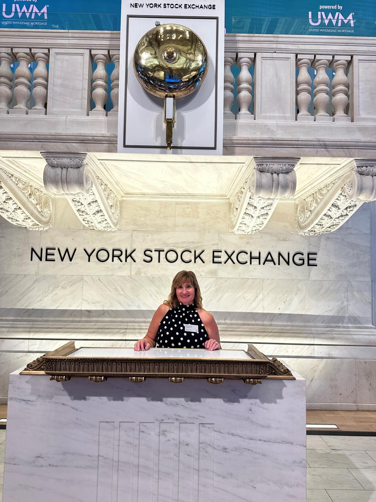 Nancy Sapper standing under the New Yorker Stock Exchange bell